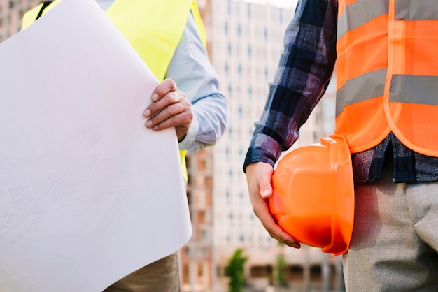 Close-up men with safety vests and helmet