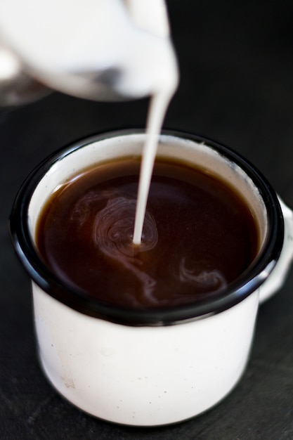 Free photo close up milk pourred in black coffee