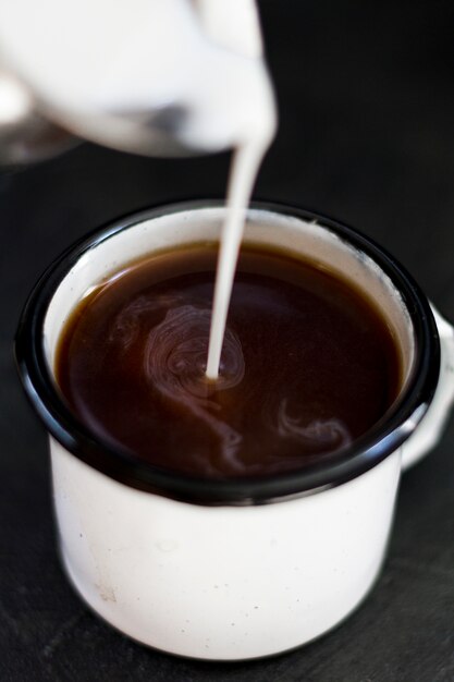 Close up milk pourred in black coffee