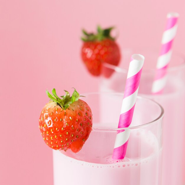 Close-up of milkshakes with straws and strawberries