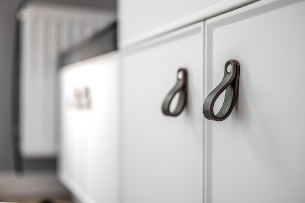 Close up of minimalistic white furniture with black handles, kitchen cabinet, details.