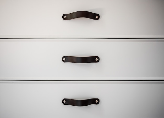 Close up of minimalistic white furniture with black handles, kitchen cabinet, details.