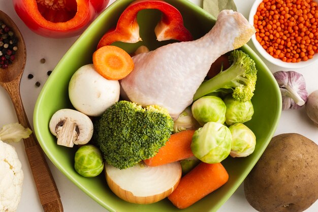 Close-up mix of vegetables in bowl with chicken drumstick