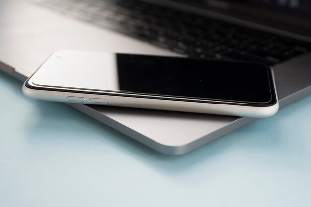 Close-up of mobile phone above laptop