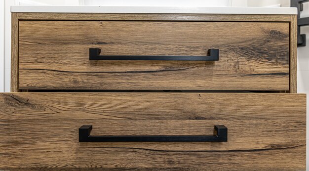 Close-up of modern dark wood furniture with black handles.
