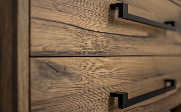 Close-up of modern dark wood furniture with black handles.