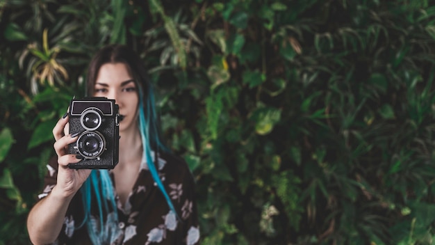 Close-up of modern woman taking picture with vintage camera