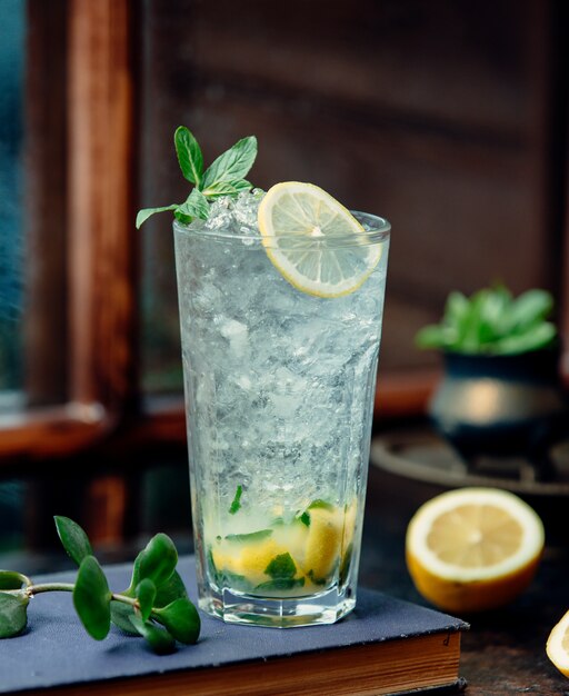 a close up of mojito glass with lemon and ice shaving