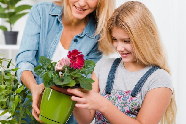 Free photo close-up mom and daughter caring flowers