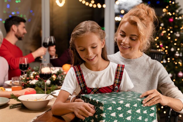 Close up mom and daughter opening gifts