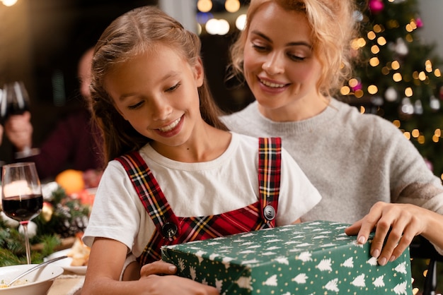 Close up mom and daughter opening gifts