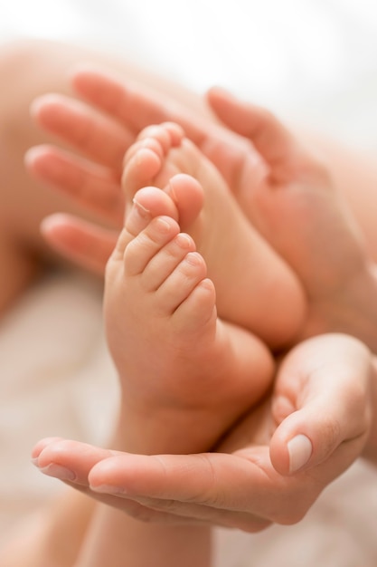 Close-up mom holding baby's feet in hands