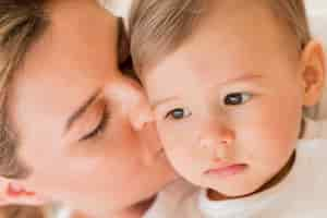 Free photo close-up mom kissing baby's cheek