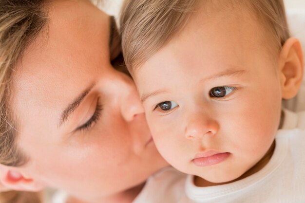 Close-up mom kissing baby's cheek