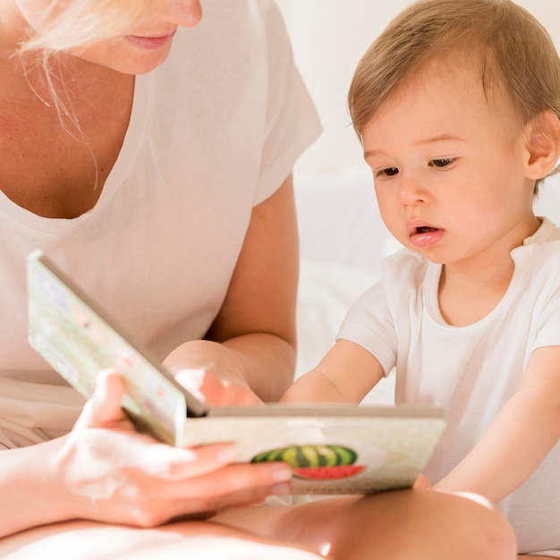 Close-up mom reading to baby in bed