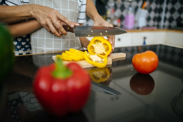 Close up of mom’s hand teaching her daughter preparing and chopping vegetable. 