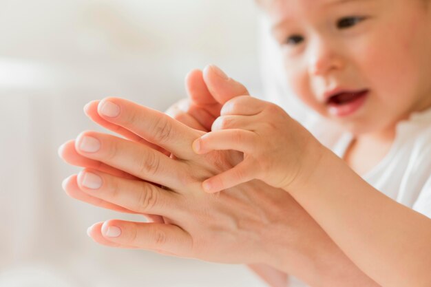 Close-up mother and baby playing with hands