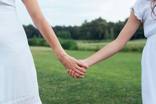 Close up mother and daughter holding hands outdoors