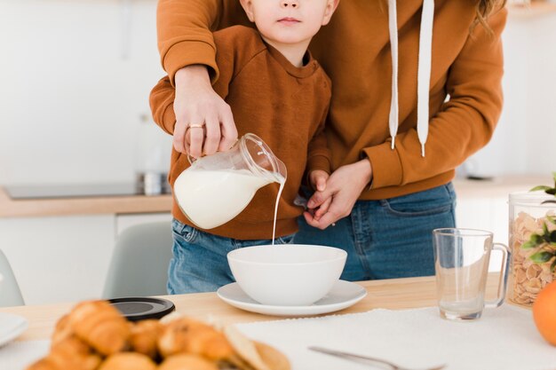 クローズアップの母と息子が牛乳を注ぐ