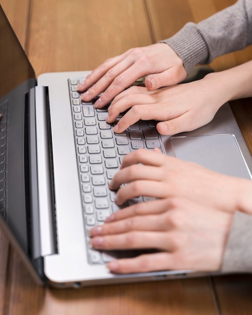 Close-up mother teaching her son how to use laptop