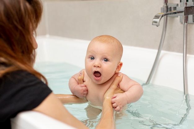 Close-up mother washing baby in bathtub