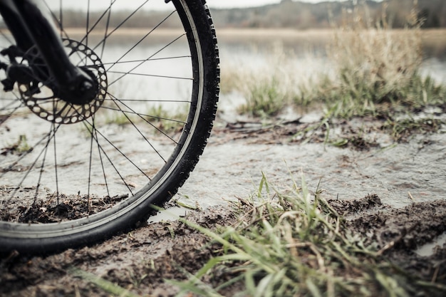 湖の近くの泥のマウンテンバイクの車輪のクローズアップ