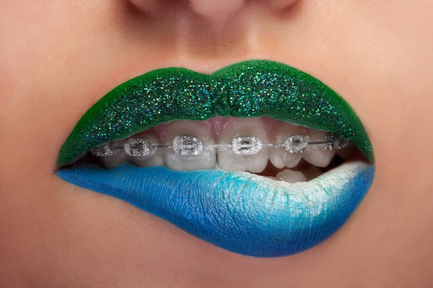 Free photo close up mouth blue and green lips with glitter brackets. fashion make up. make up addiction. artistic make up. macro shooting. sensuality and fashion concept