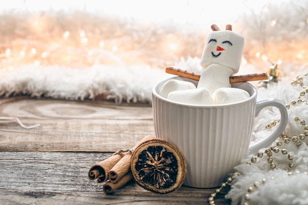 Бесплатное фото Закройте кружку горячего напитка с зефирным снеговиком на размытом фоне