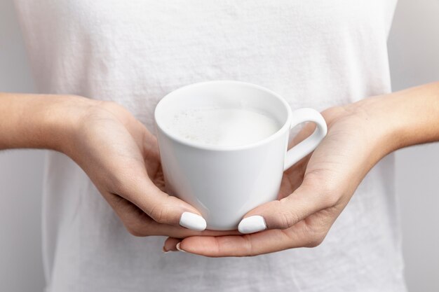 Close-up of mug with milk held in hands
