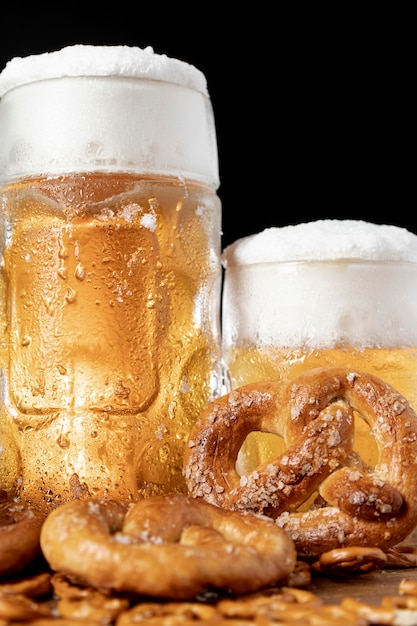 Free photo close-up mugs of beer with foam and pretzels