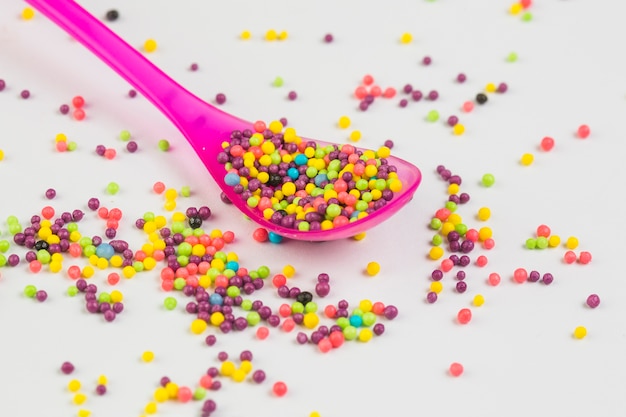 Close-up of multi colored sweet sugar balls in plastic spoon