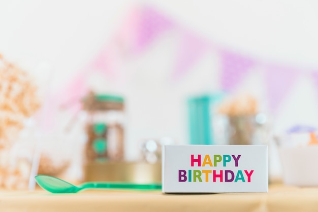 Close-up of multicolored happy birthday text on box with spoon