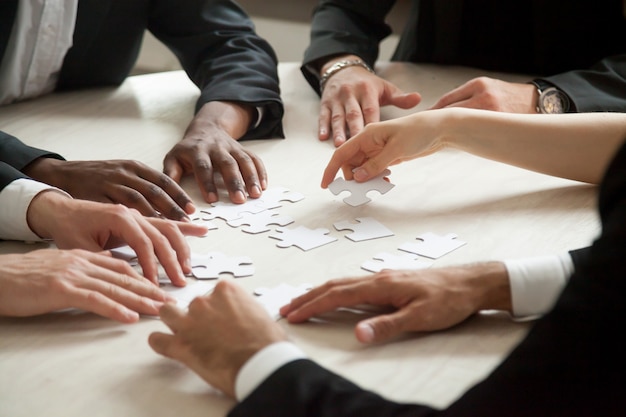 Close up of multiethnic team solving blank puzzle game.