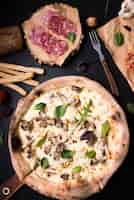 Foto gratuita close-up di pizza ai funghi; fette di peperoni; grissini e forchetta sul bancone