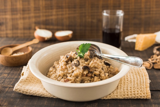 Close-up of mushroom risotto in white bowl with spoon on napkin over the table