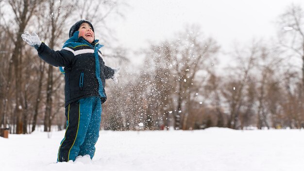 雪の中で遊んでいるn幸せな子供を閉じます