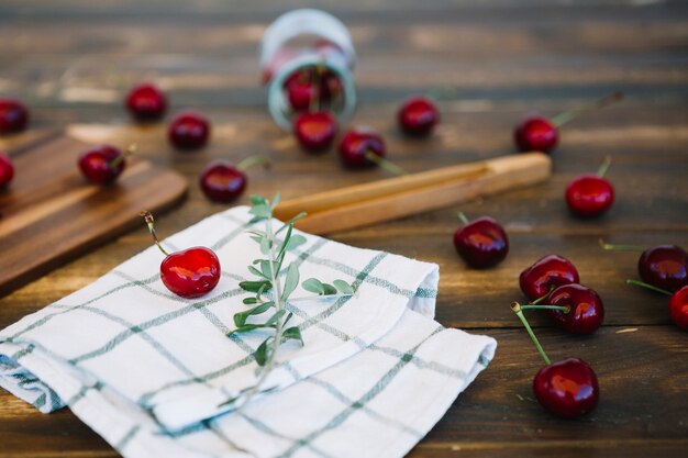 Close-up of napkin and scattered red cherries on wooden desk