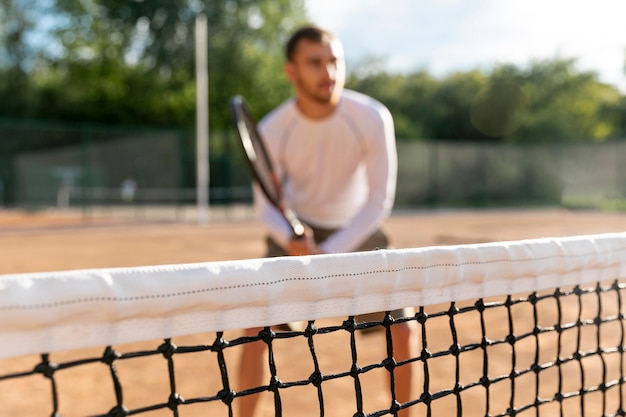 Foto gratuita rete del primo piano con giocare a tennis defocused dell'uomo