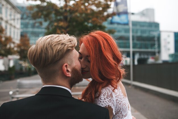 Close-up of newlyweds kissing with city background