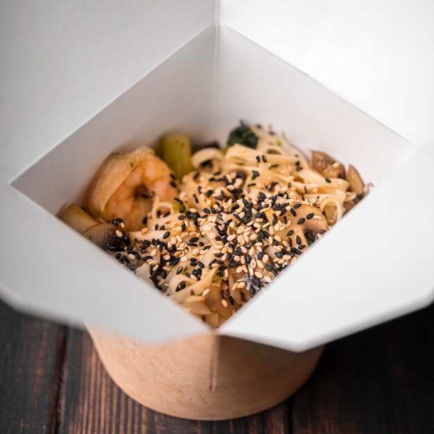 Close-up of noodles in box with sesame seeds and chopsticks