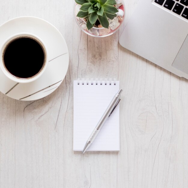 Foto gratuita taccuino del primo piano vicino a caffè e computer portatile