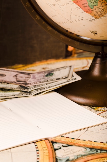 Close-up of notepad, banknotes and globe on map