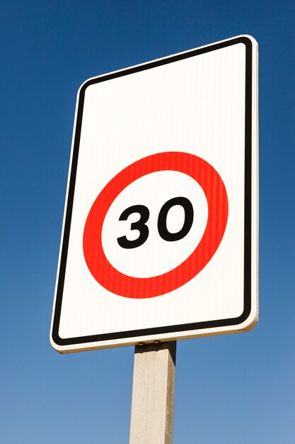 Close-up of number 30 traffic limit sign against blue sky