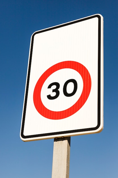 Close-up of number 30 traffic limit sign against blue sky