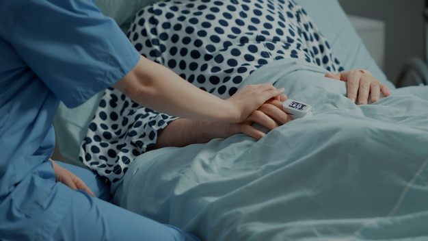Close up of nurse comforting ill patient in hospital ward