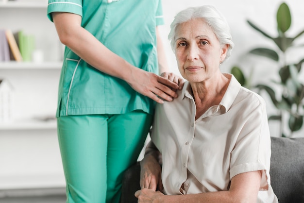 Free photo close-up of nurse standing with senior female patient sitting on sofa