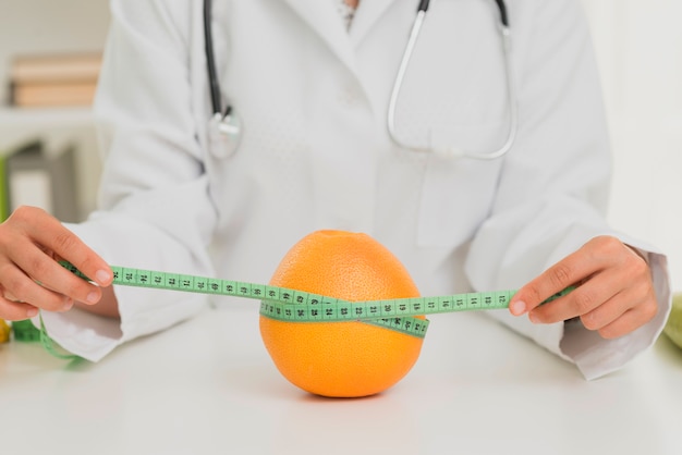 Close-up nutritionist measuring an orange