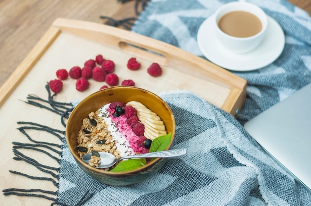 Free photo close-up of oatmeal bowl with raspberries on wooden tray