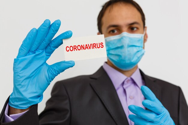 Крупный план бизнесмена в костюме в защитной маске, готовьтесь к коронавирусу и в 2.5 часа дня, сражающегося на сером фоне. концепция здравоохранения.