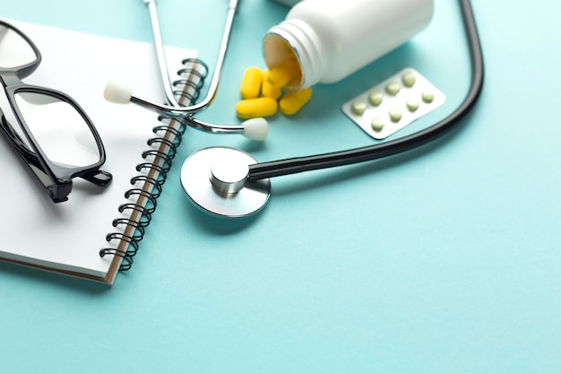 Бесплатное фото Крупный план стола врача с таблетками и спиральным блокнотом
